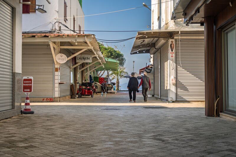 A scooter crosses the end of the street, the turquoise boat sits in the marina, and a couple walk down towards the water. (3 of 3)