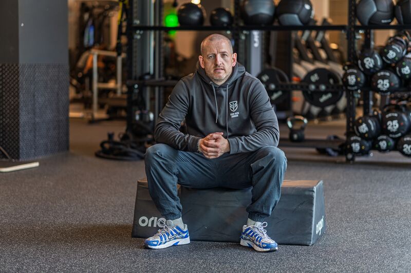 Stephen Armour, personal trainer, seated on a plyo box in his gym